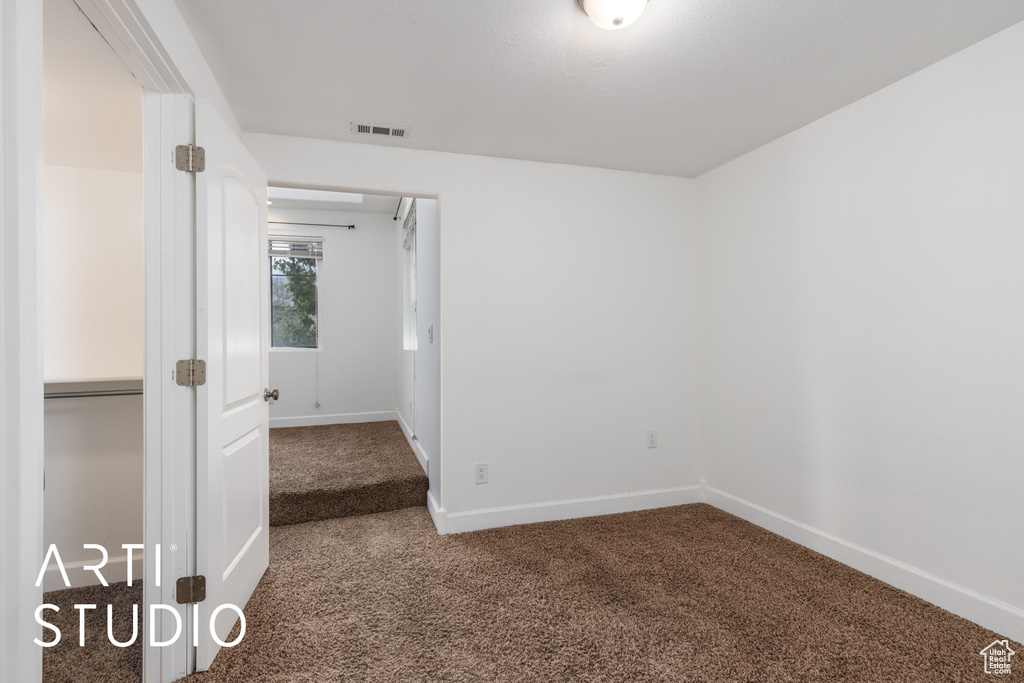 Empty room with carpet floors, baseboards, and visible vents