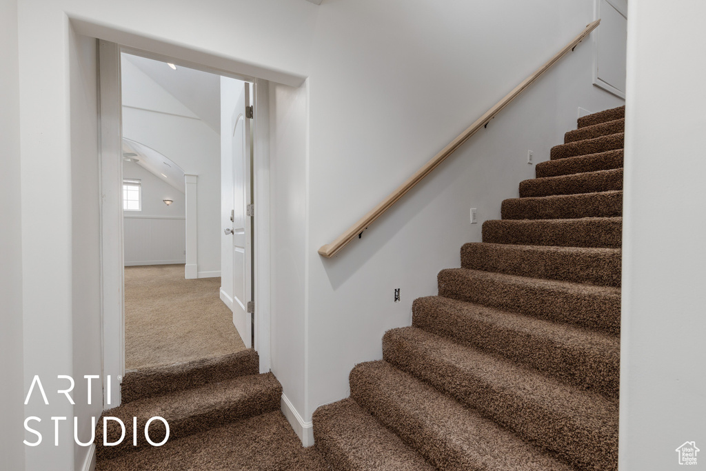Stairway with baseboards, carpet floors, and arched walkways
