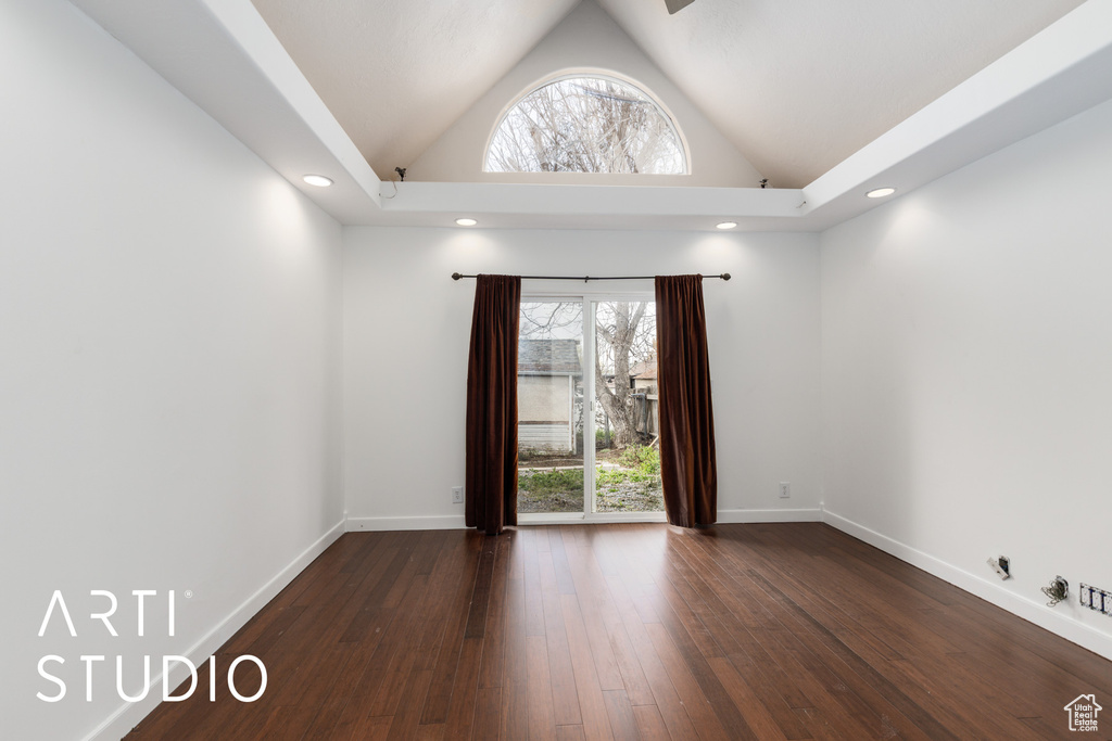 Spare room featuring lofted ceiling, baseboards, plenty of natural light, and dark wood finished floors