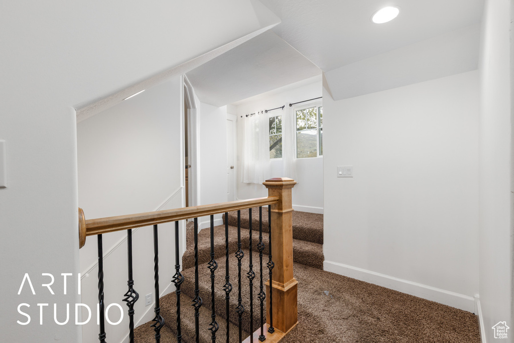 Hallway with carpet, an upstairs landing, baseboards, and lofted ceiling