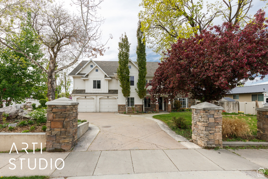 View of front of house with an attached garage, driveway, roof with shingles, and stone siding