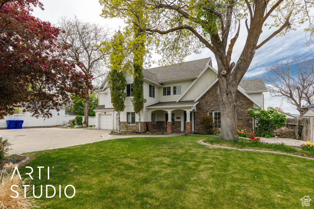 Traditional-style house featuring fence, driveway, stone siding, and a front yard