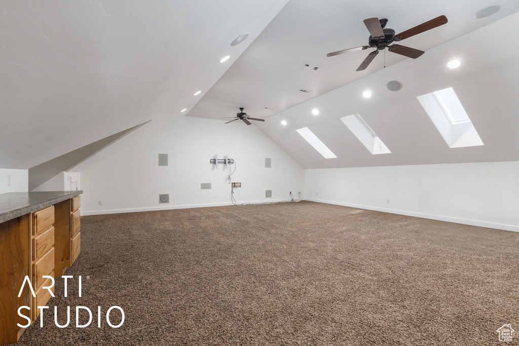 Bonus room featuring baseboards, lofted ceiling with skylight, ceiling fan, and carpet floors
