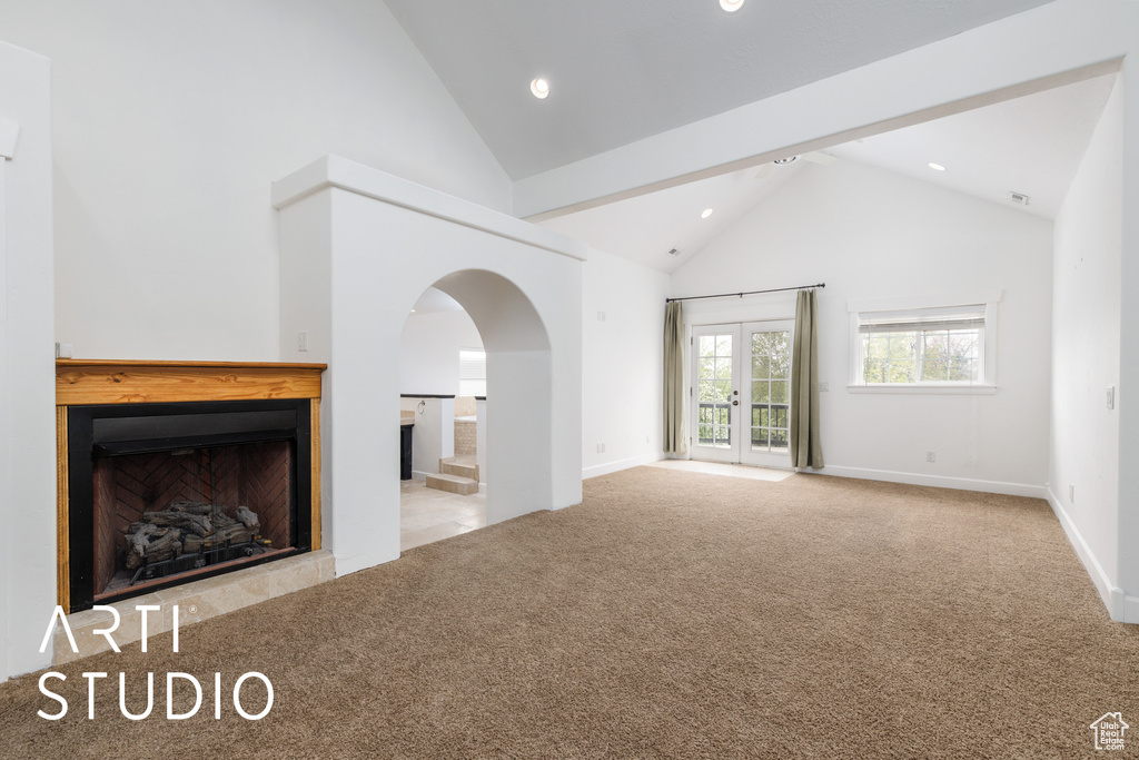 Unfurnished living room with carpet, high vaulted ceiling, recessed lighting, arched walkways, and baseboards
