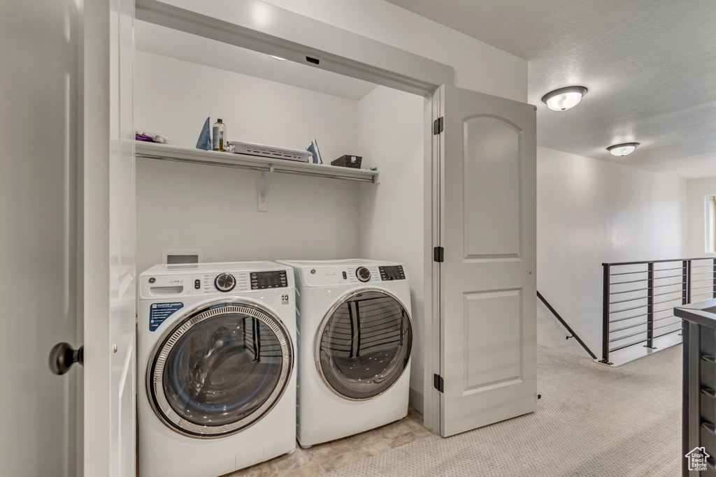 Laundry room with laundry area, light carpet, and separate washer and dryer