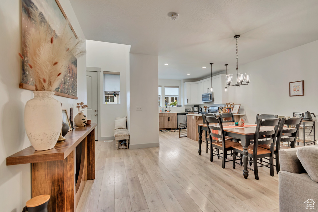 Dining area featuring a notable chandelier, light wood-type flooring, baseboards, and recessed lighting