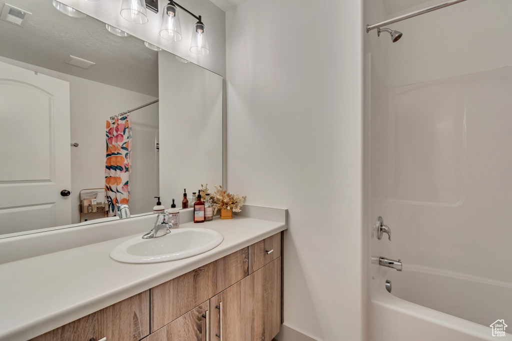 Bathroom featuring vanity, shower / tub combo with curtain, and visible vents