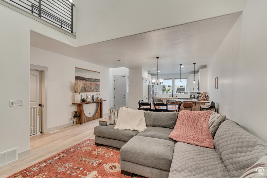 Living room featuring recessed lighting, baseboards, an inviting chandelier, visible vents, and light wood-type flooring