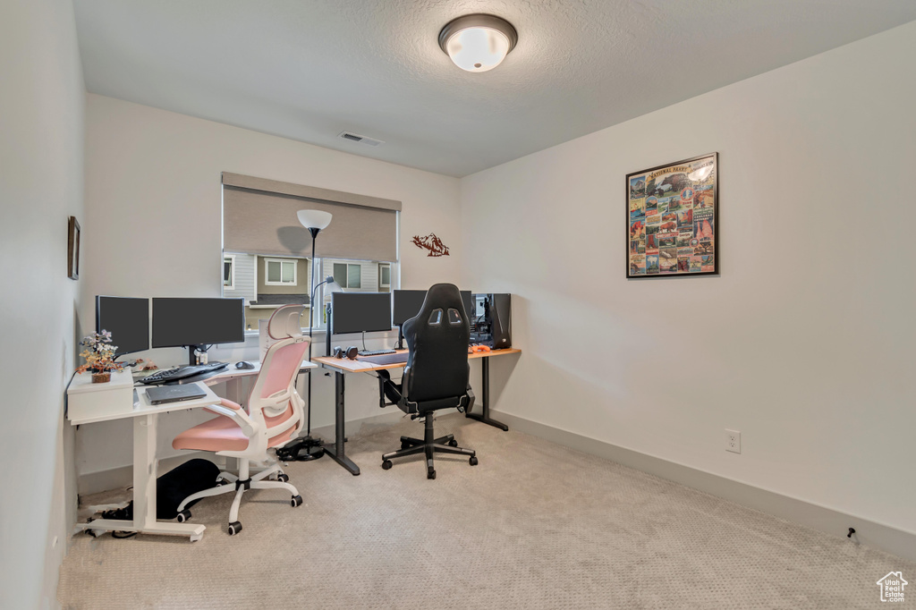 Office area featuring baseboards, a textured ceiling, visible vents, and carpet floors
