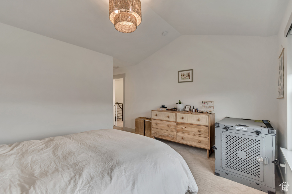 Carpeted bedroom with an inviting chandelier and lofted ceiling