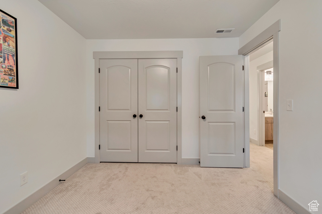 Unfurnished bedroom with light colored carpet, a closet, visible vents, and baseboards