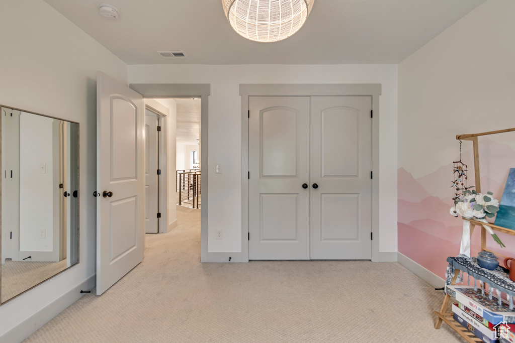 Unfurnished bedroom with light colored carpet, a closet, baseboards, and visible vents