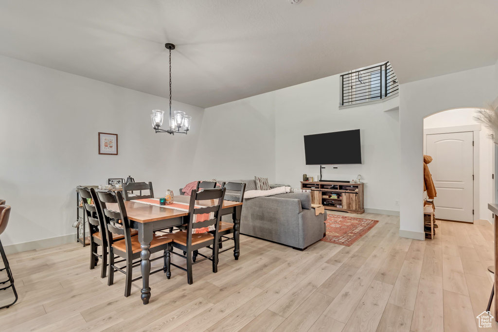Dining area with light wood-type flooring, baseboards, arched walkways, and a notable chandelier