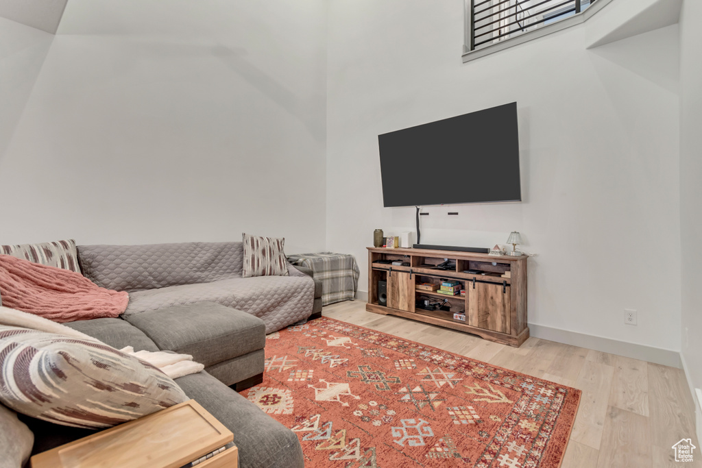 Living room with baseboards, a high ceiling, and wood finished floors
