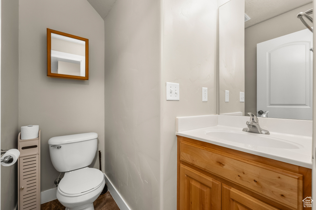 Half bath featuring baseboards, toilet, and vanity