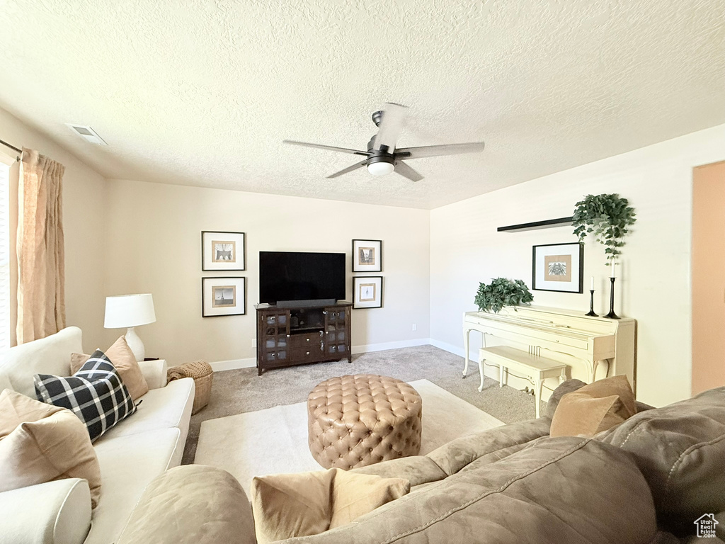 Living room with a ceiling fan, light carpet, and a textured ceiling