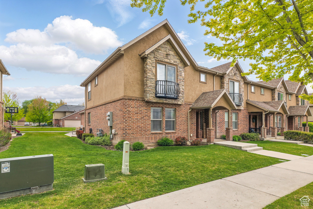 View of front of house with a balcony, a front lawn, stucco siding, stone siding, and a residential view