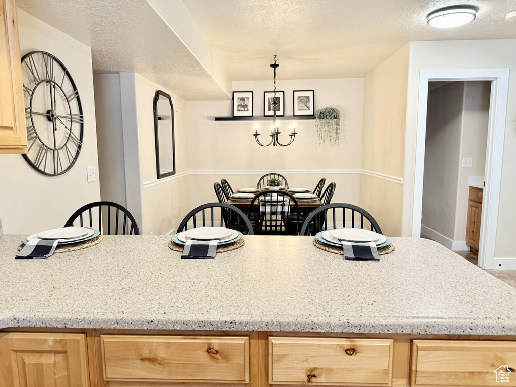 Kitchen featuring light brown cabinets, a chandelier, and light stone countertops