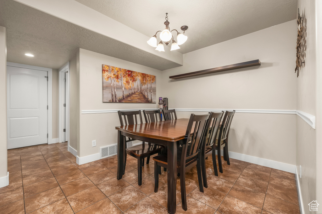 Dining space featuring a chandelier, baseboards, and a textured ceiling