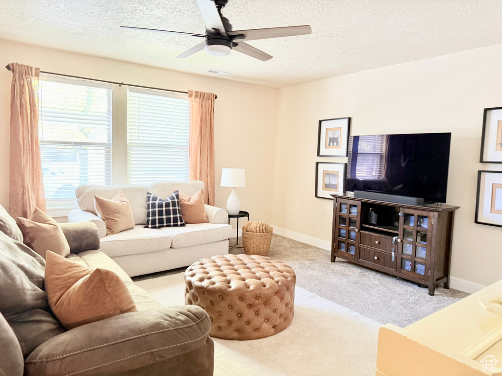 Living room featuring a textured ceiling, carpet, and a ceiling fan