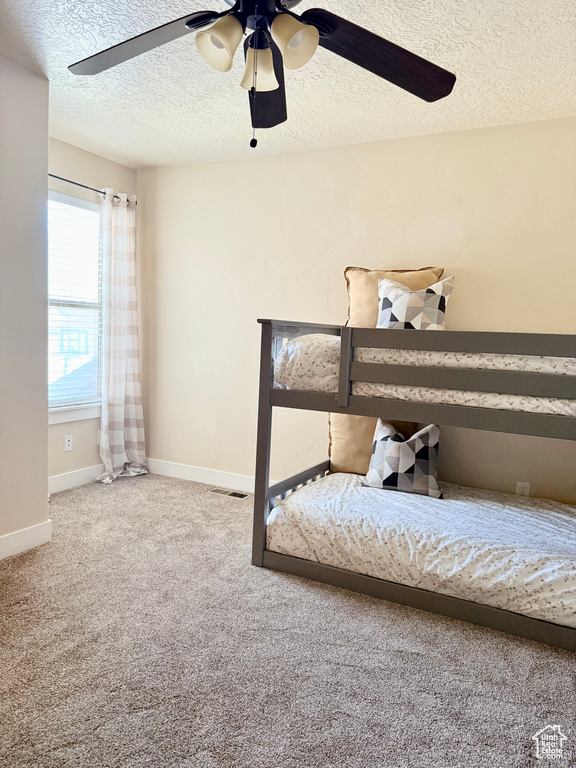 Bedroom featuring a textured ceiling, a ceiling fan, and carpet floors