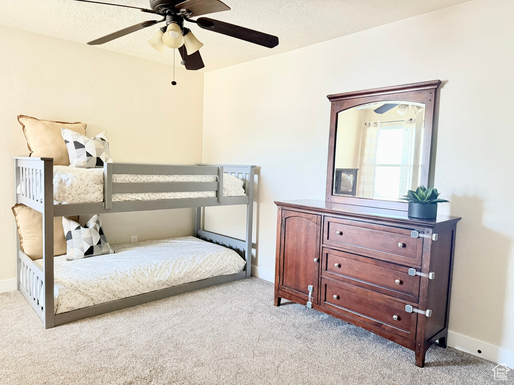 Bedroom with light colored carpet, ceiling fan, and a textured ceiling