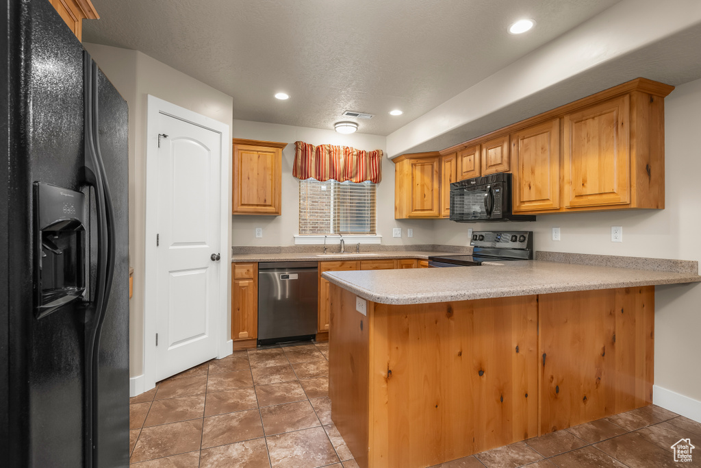 Kitchen with black appliances, a peninsula, a sink, baseboards, and light countertops