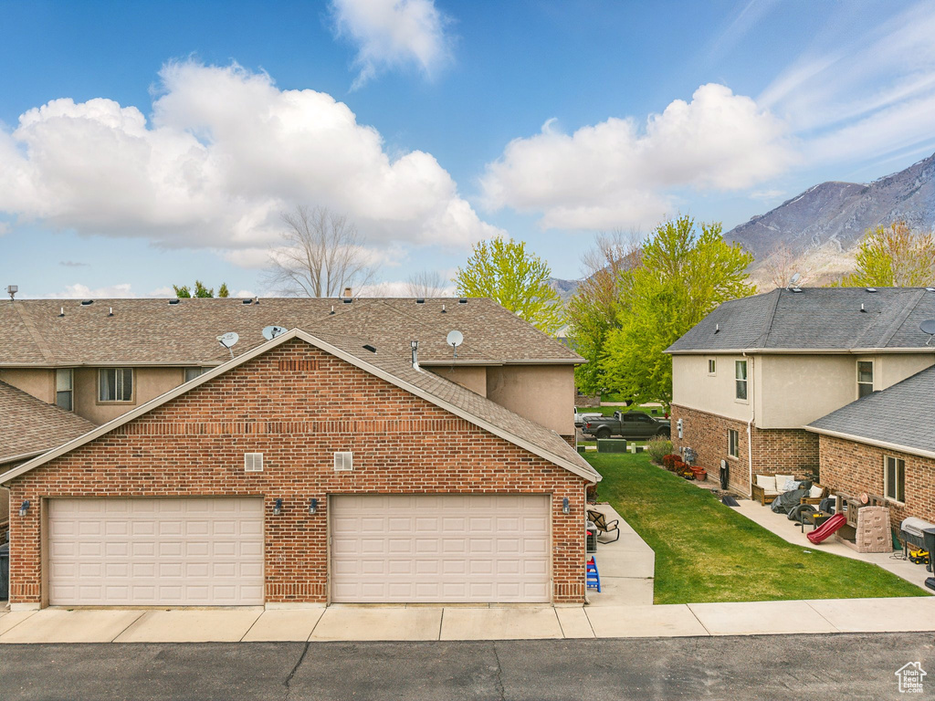 View of front of house featuring a mountain view, a front lawn, brick siding, and a shingled roof
