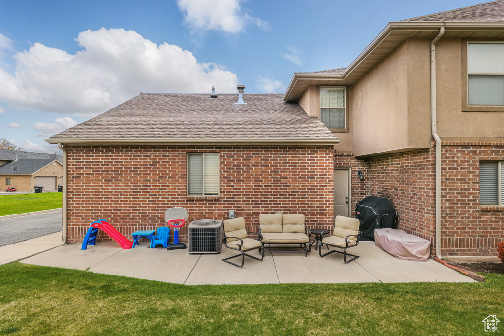 Back of property featuring cooling unit, roof with shingles, a patio, and brick siding