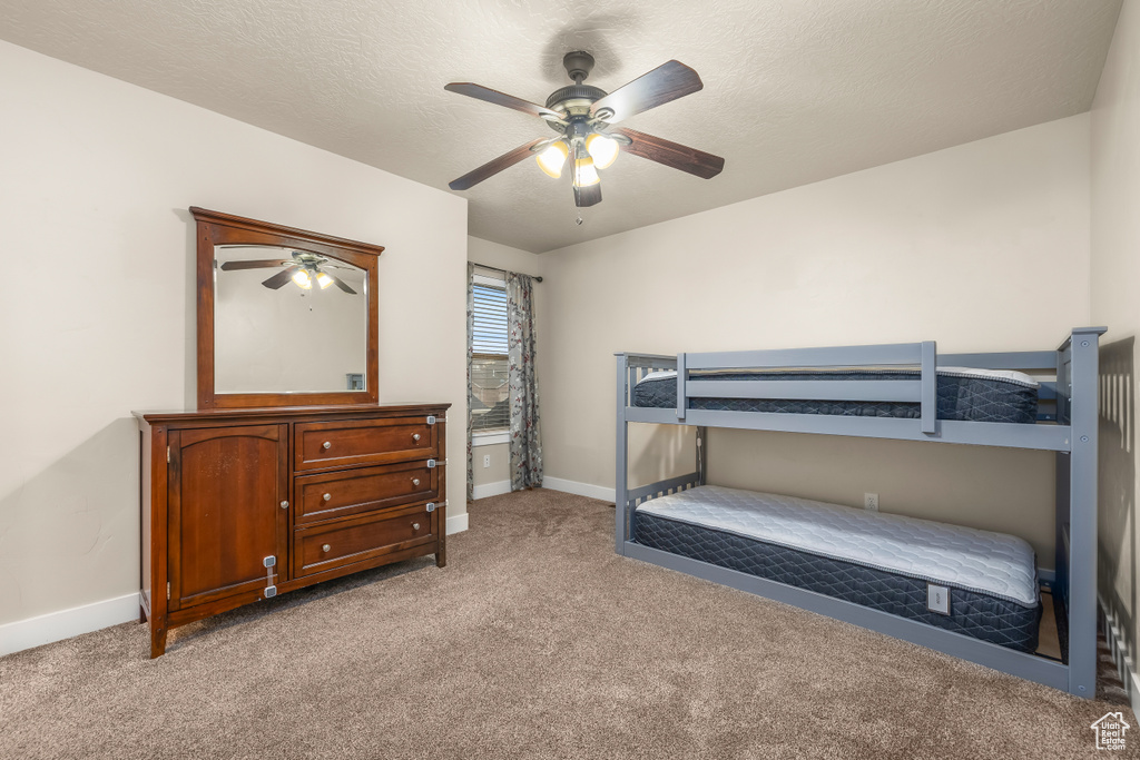 Bedroom featuring light carpet, baseboards, ceiling fan, and a textured ceiling