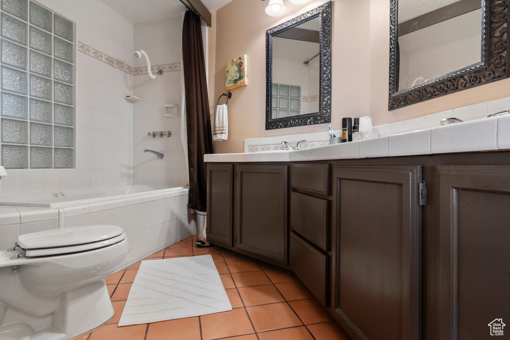Bathroom with toilet, tiled shower / bath combo, tile patterned floors, and vanity
