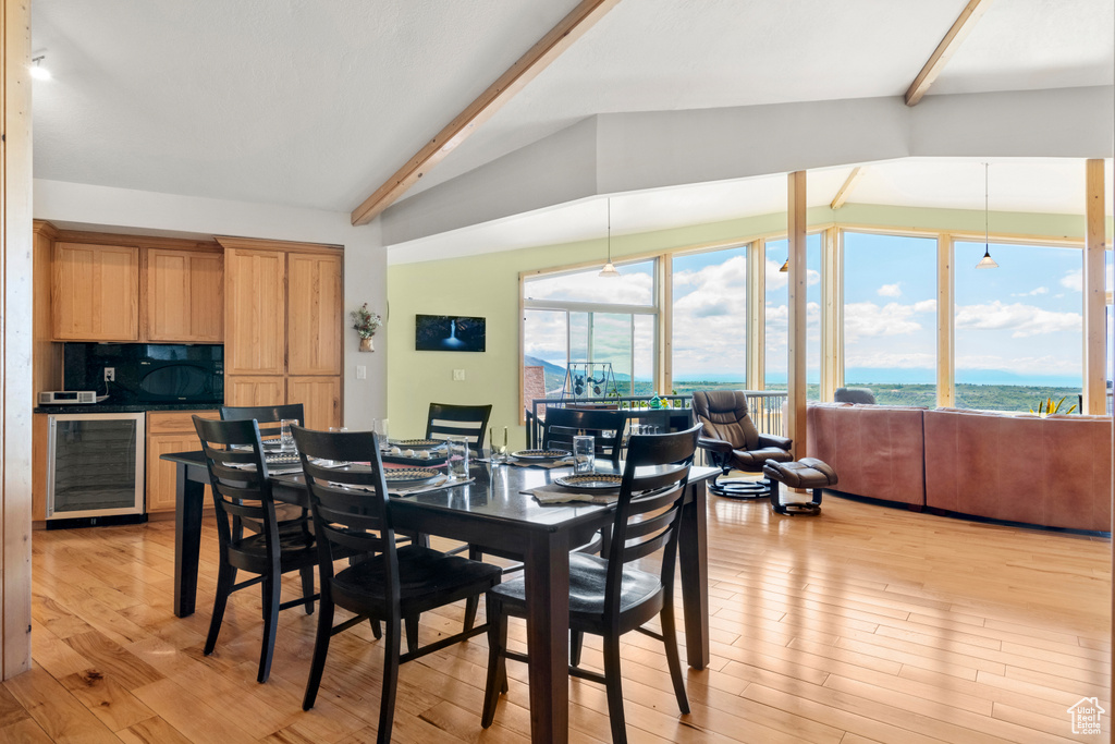 Dining room with beverage cooler, light wood finished floors, and a water view