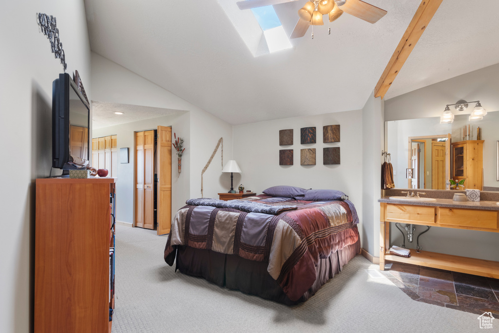 Bedroom featuring a skylight, a sink, light carpet, baseboards, and high vaulted ceiling