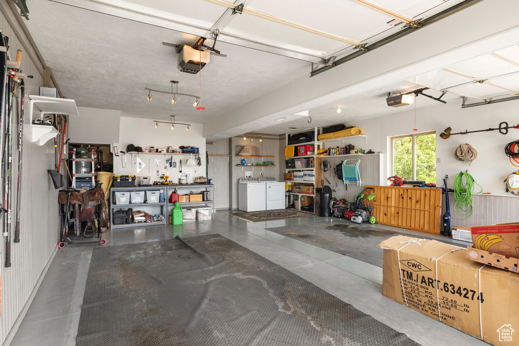 Garage featuring separate washer and dryer, a garage door opener, and a workshop area