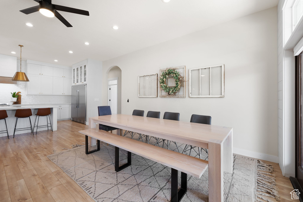 Dining space featuring a ceiling fan, arched walkways, baseboards, recessed lighting, and light wood-style flooring
