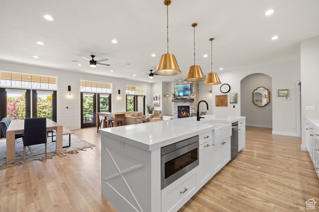 Kitchen featuring appliances with stainless steel finishes, a fireplace, a sink, light countertops, and recessed lighting