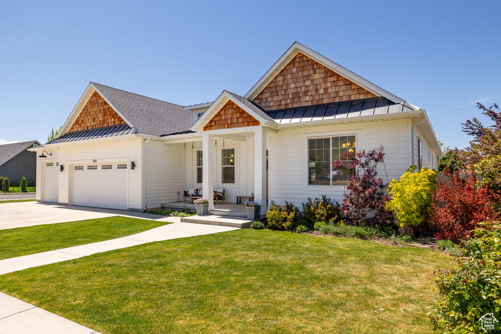 Craftsman house featuring a standing seam roof, metal roof, a garage, a front lawn, and concrete driveway