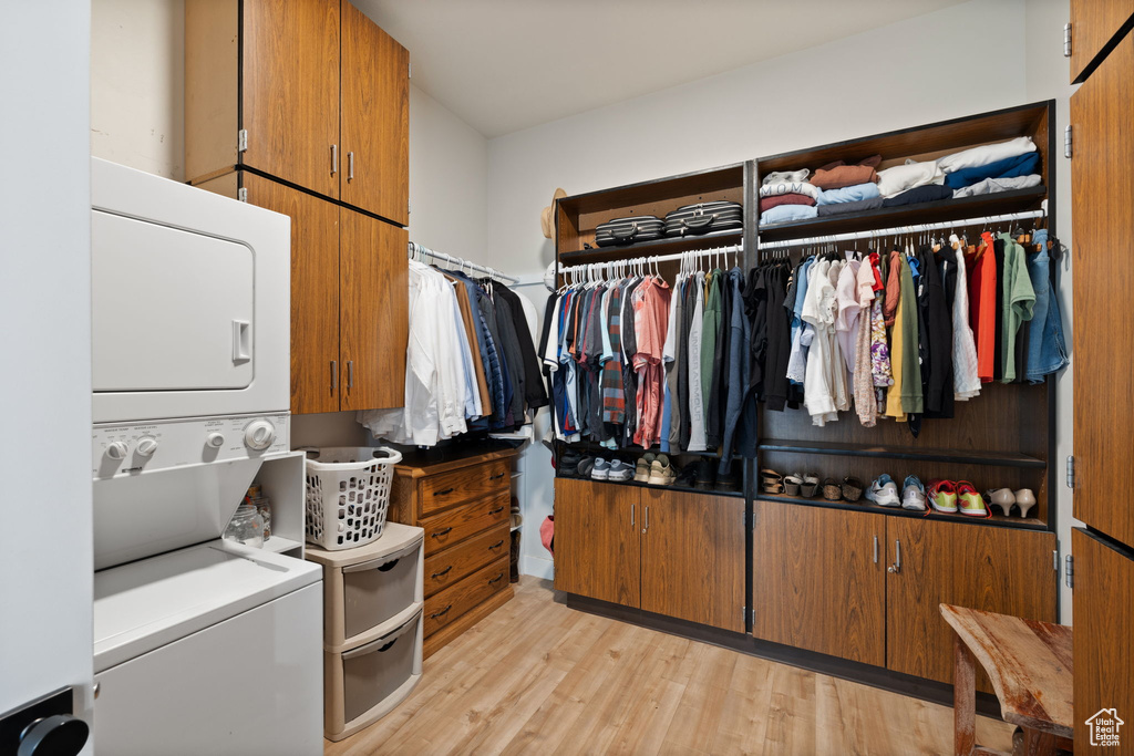 Walk in closet featuring light wood-style floors and stacked washing maching and dryer