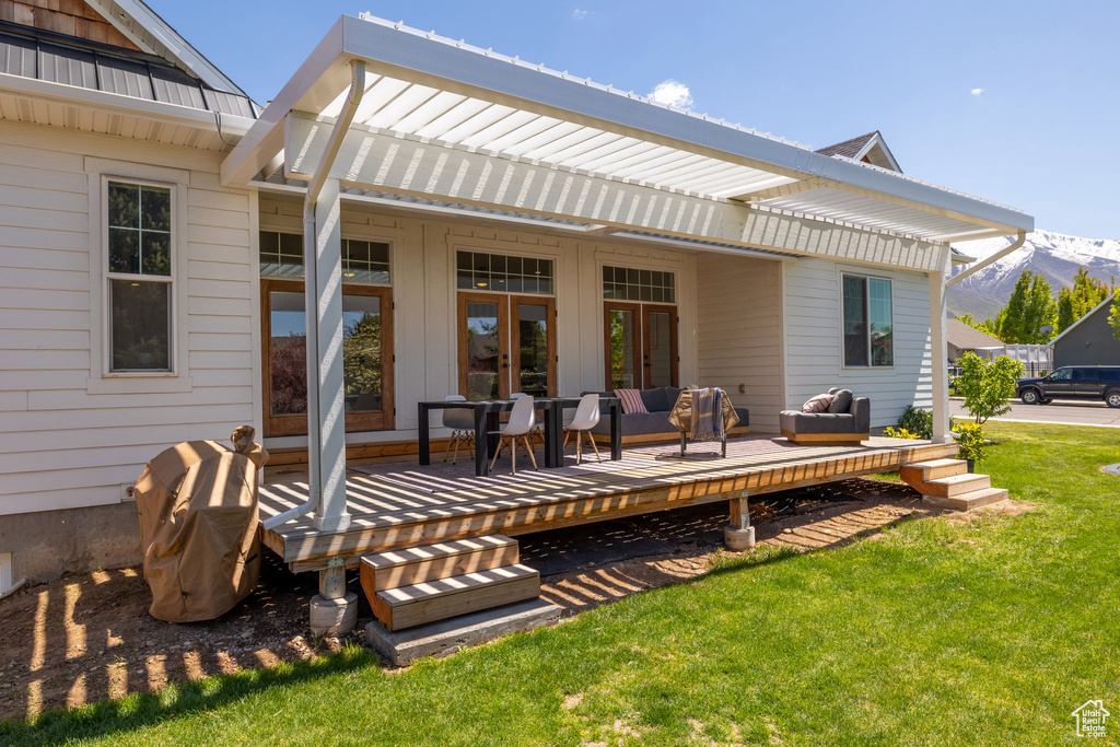 Back of property featuring a lawn, a deck with mountain view, outdoor lounge area, and metal roof