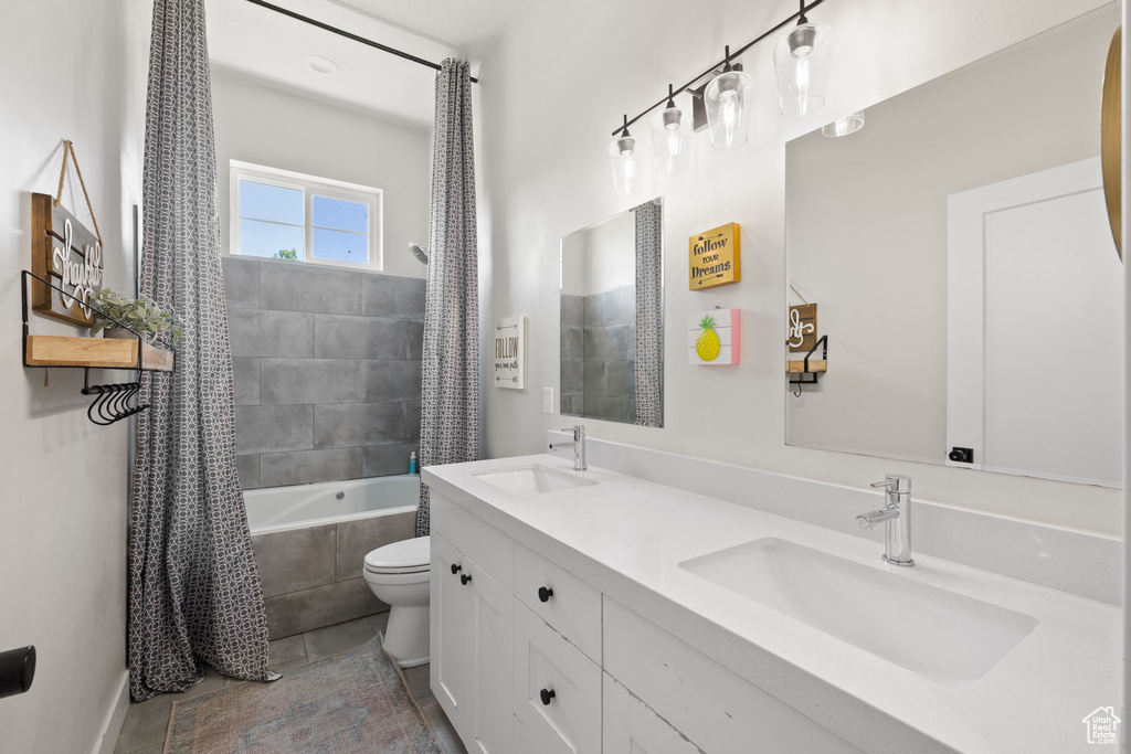 Full bath featuring tile patterned flooring, a sink, tiled shower / bath, and toilet