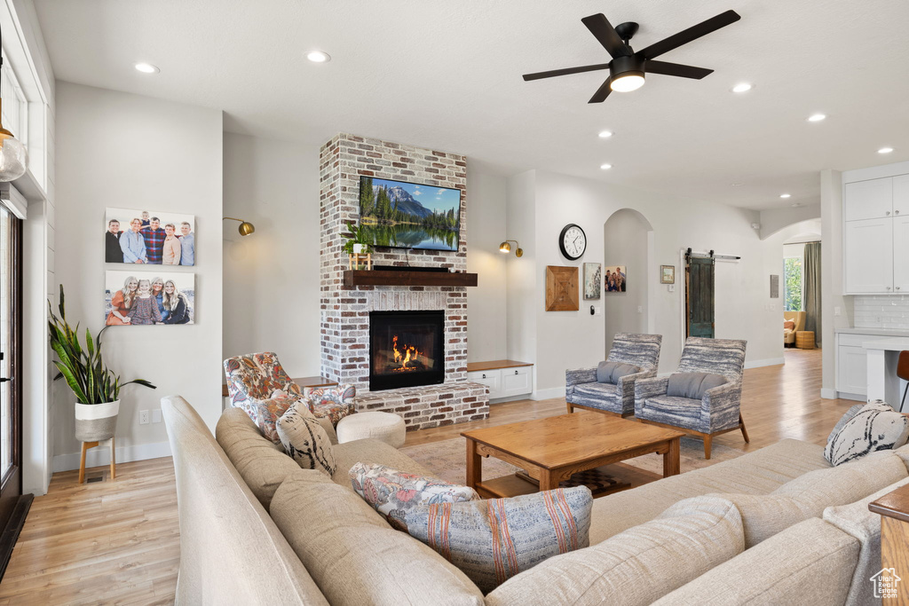 Living room featuring arched walkways, recessed lighting, and light wood-style flooring