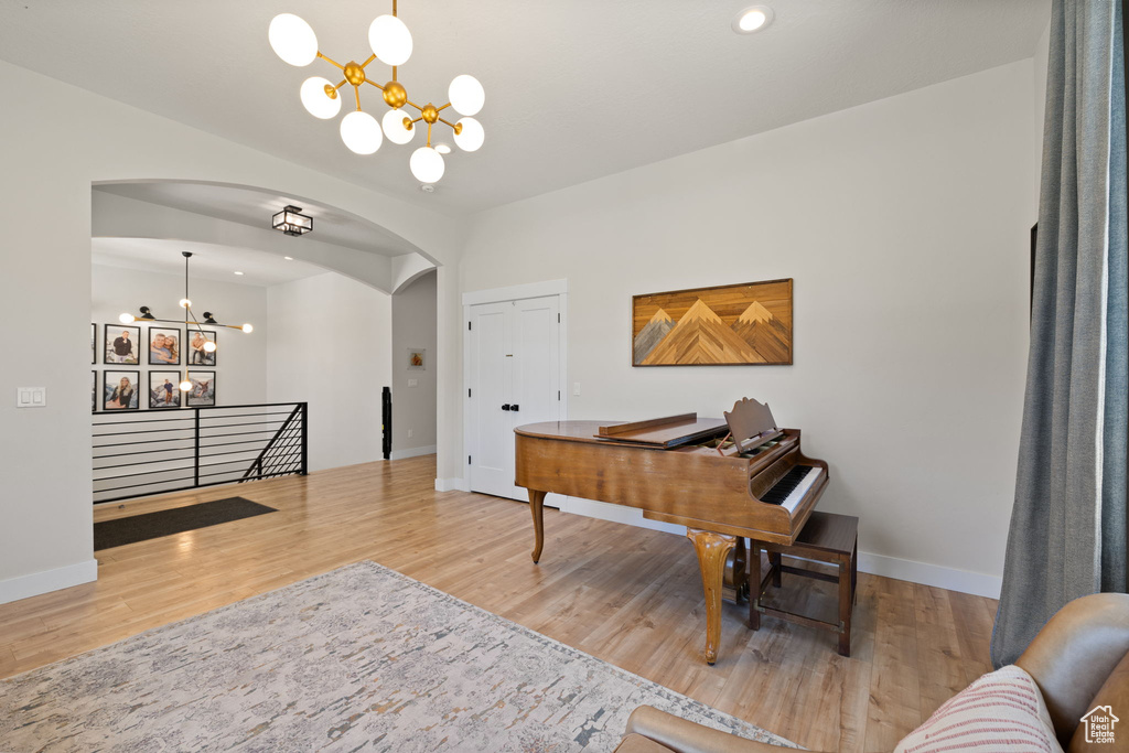 Office space featuring an inviting chandelier, arched walkways, baseboards, and wood finished floors