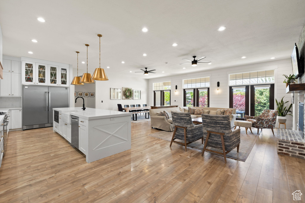 Kitchen with ceiling fan, appliances with stainless steel finishes, light countertops, open floor plan, and recessed lighting