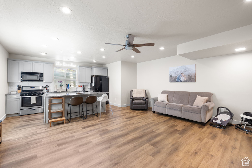 Living area with recessed lighting, baseboards, ceiling fan, and light wood-style flooring