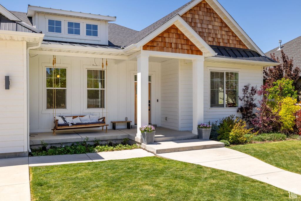 View of front of property with a standing seam roof, metal roof, a porch, and a front lawn