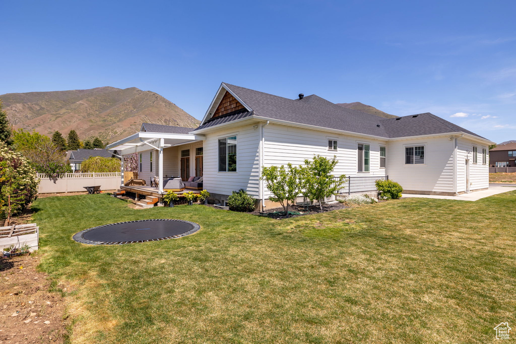 Back of house featuring fence, an outdoor hangout area, a yard, a deck with mountain view, and a shingled roof