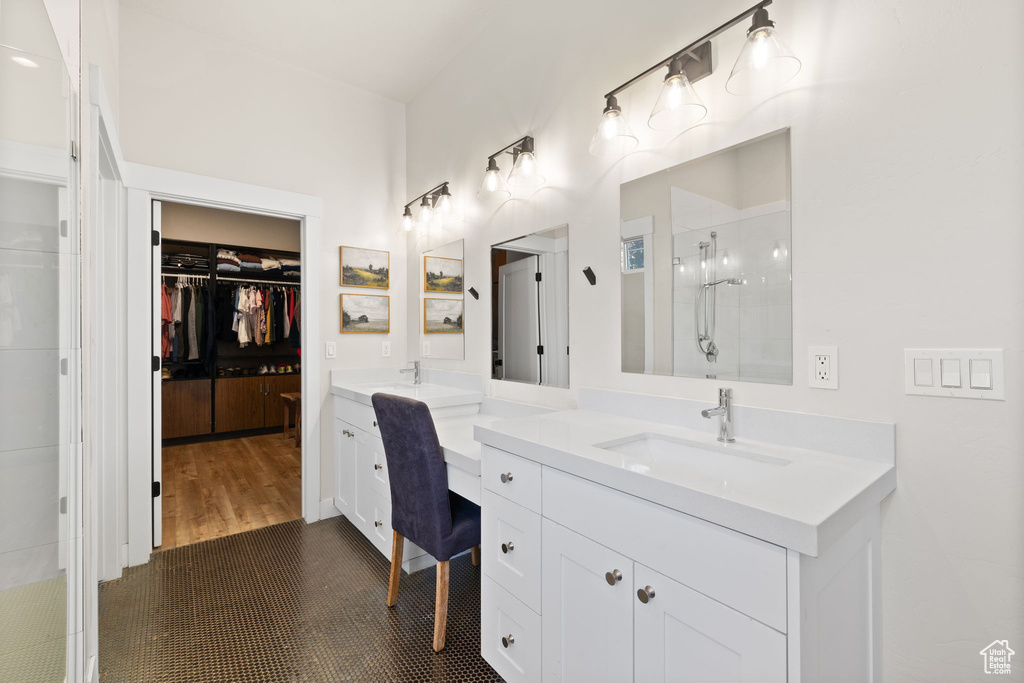 Full bathroom with tiled shower, two vanities, a sink, and a spacious closet