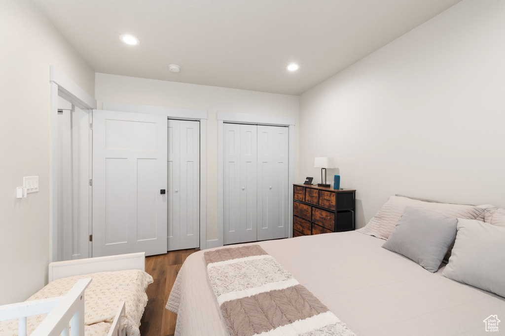 Bedroom with wood finished floors, recessed lighting, and two closets
