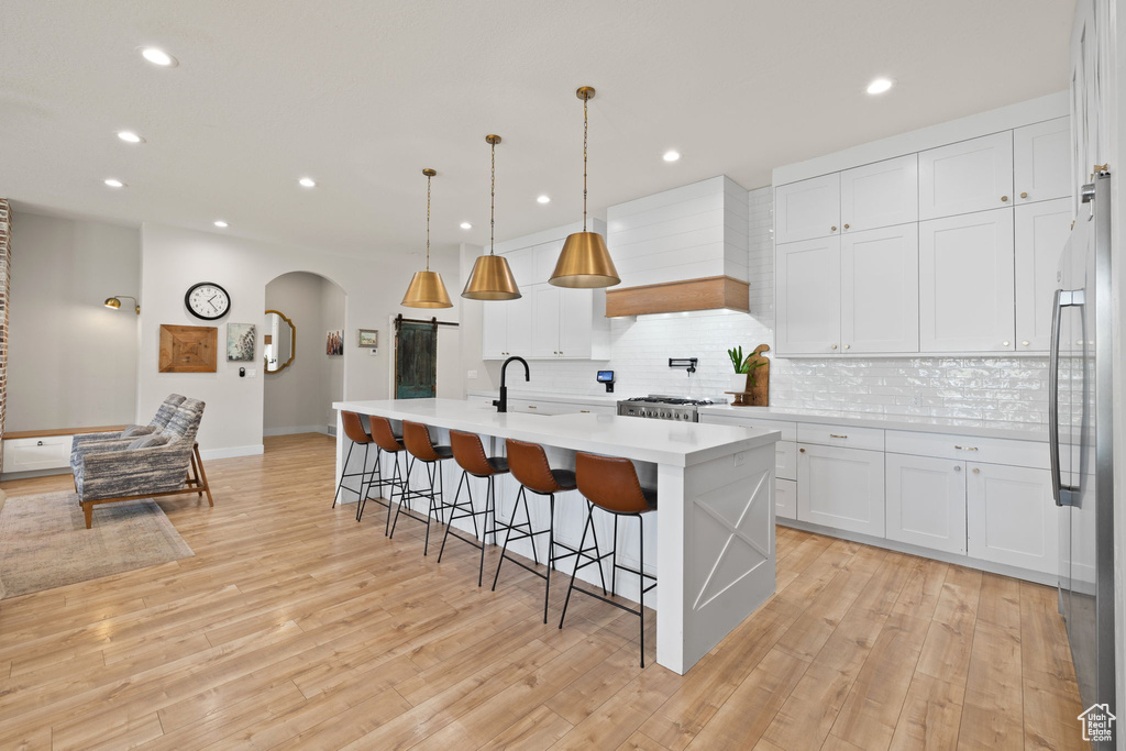 Kitchen with recessed lighting, arched walkways, custom exhaust hood, and stainless steel fridge
