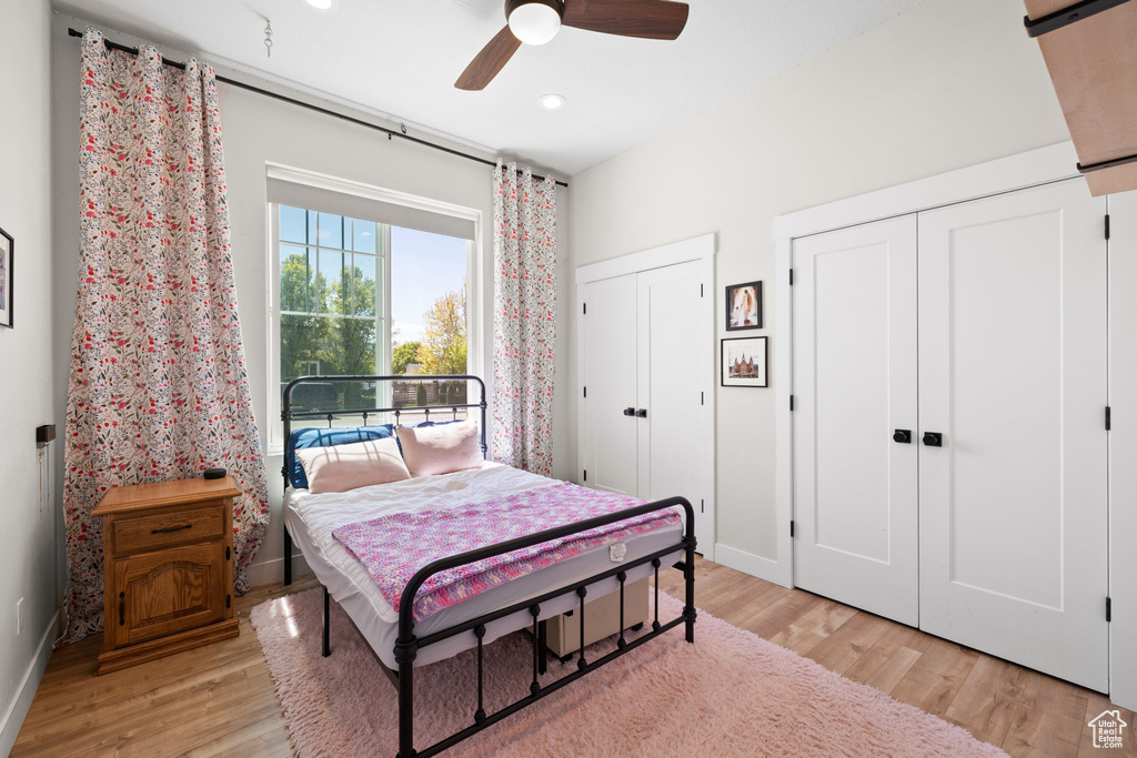 Bedroom featuring a ceiling fan, baseboards, two closets, light wood-style floors, and recessed lighting